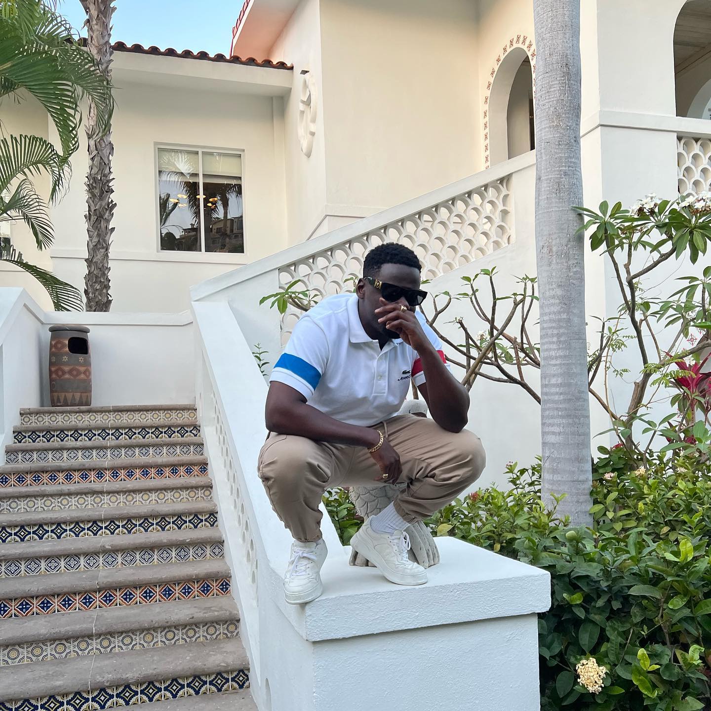 Ο Daniel Kaluuya οκλαδόν στη σκάλα με μαύρα γυαλιά ηλίου