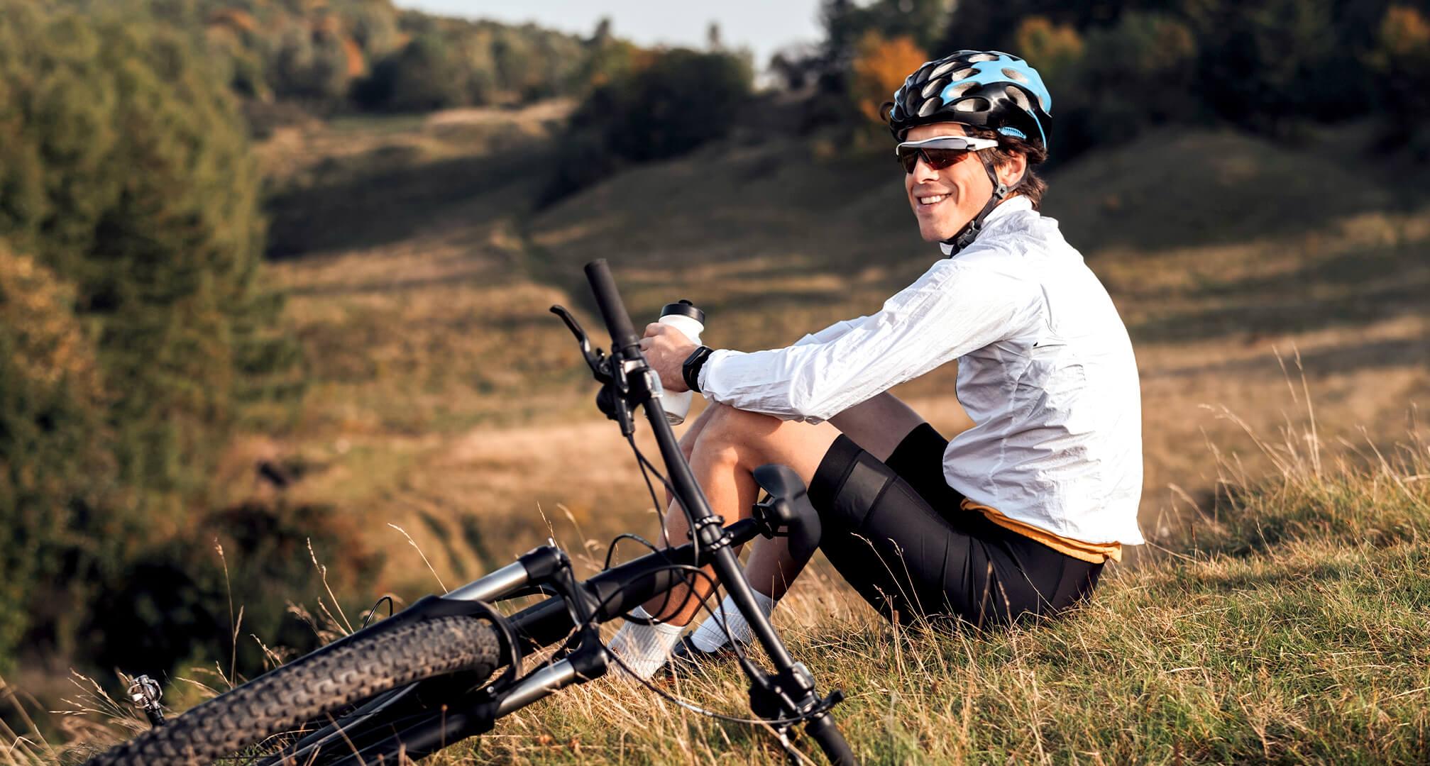 άτομο κάθεται σε λόφο με ποδήλατο βουνού και φοράει γυαλιά ηλίου